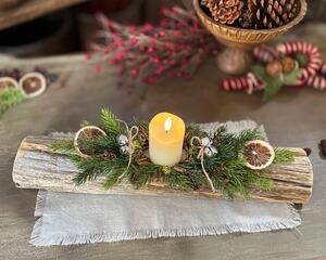A Christmas yule log centerpiece with a battery candle, oranges slcies, jingle bells and real touch greenery